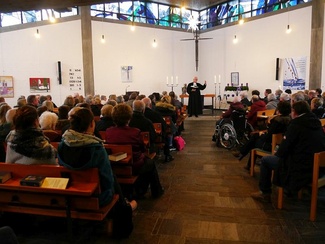 In der voll besetzten Kirche verfolgen Zuhörer aufmerksam die Predigt.